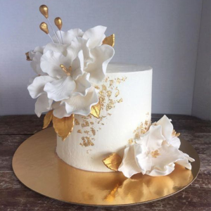 Elegant one-tier engagement cake with white sugar flowers and gold leaf accents
