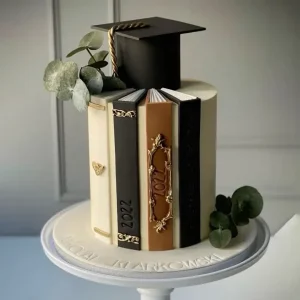 Tall fondant graduation cake shaped like vertical books with a cap on top