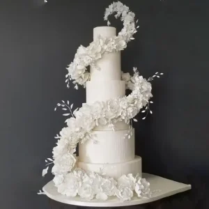 Elegant four-tier white wedding cake with zig-zag floral arrangement of handcrafted sugar flowers