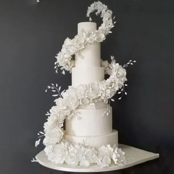 Elegant four-tier white wedding cake with zig-zag floral arrangement of handcrafted sugar flowers