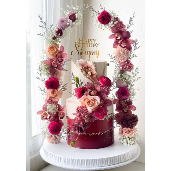 Luxurious flower tiered birthday cake decorated with real roses and floral arch