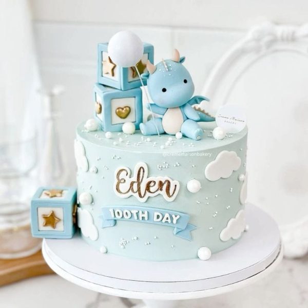 Blue dino baby cake with fondant dinosaur, balloon, clouds, and name tag for celebration