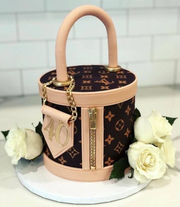 Luxury LV handbag cake with blush pink details, edible gold zipper, and white roses