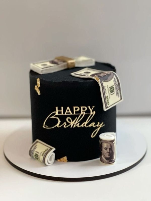Black birthday cake with edible money decorations and gold accents
