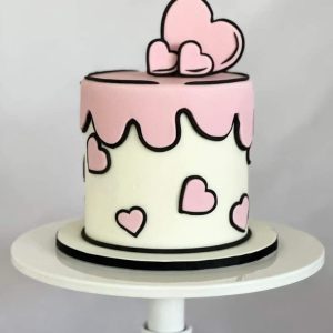 Pink and white pop art comic-style cake with pink hearts and fondant heart topper