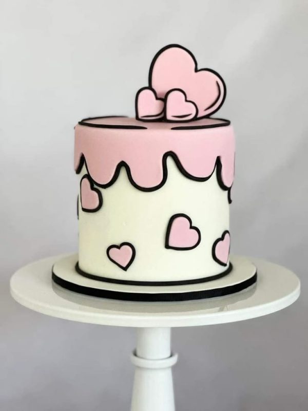 Pink and white pop art comic-style cake with pink hearts and fondant heart topper