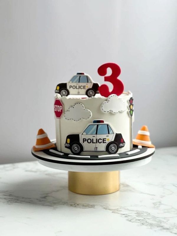 Police-themed kids birthday cake with printed police car and traffic sign toppers