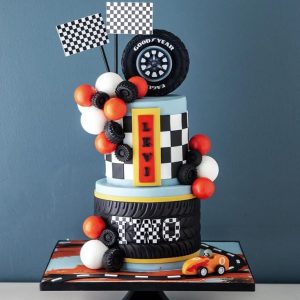 Race Car Cake with edible tire topper, checkered flags, balloons, and fondant car – custom birthday cake for kids