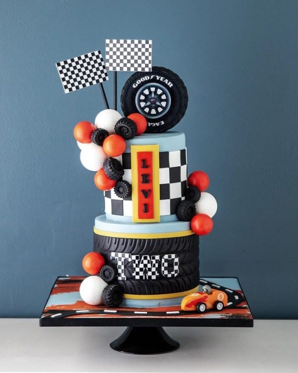 Race Car Cake with edible tire topper, checkered flags, balloons, and fondant car – custom birthday cake for kids