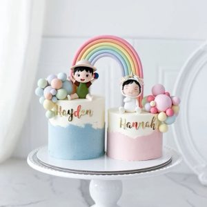 Pastel twin birthday cake with rainbow arch, fondant baby toppers, and name personalization for boy and girl twins