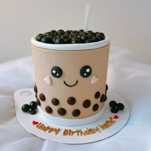 Milk tea themed cake with chocolate boba pearls and a smiling kawaii face